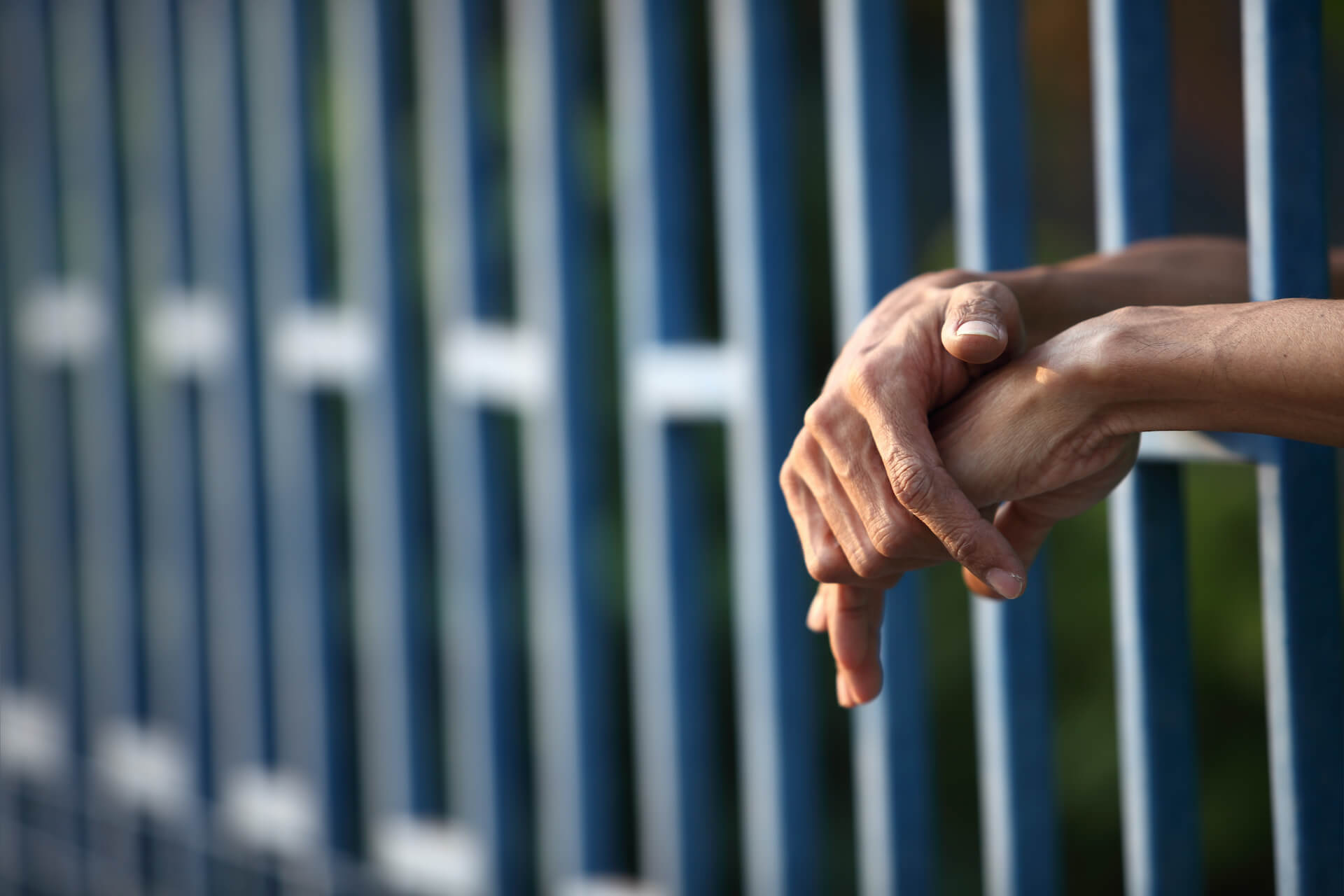 paire de mains derrières les barreaux d’une prison